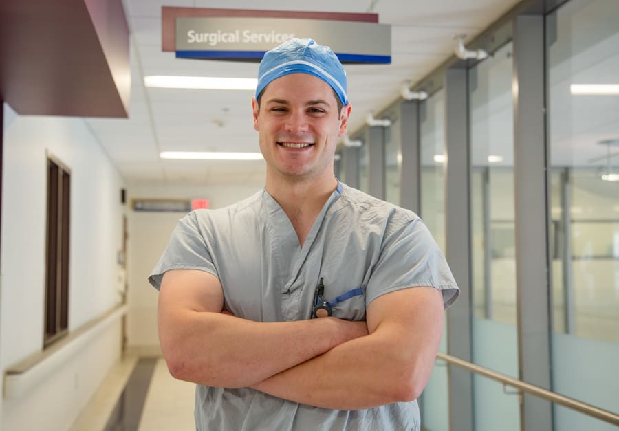 Medical learner Grant Sweeny in scrubs outside the surgery unit at Marotta Family Hospital