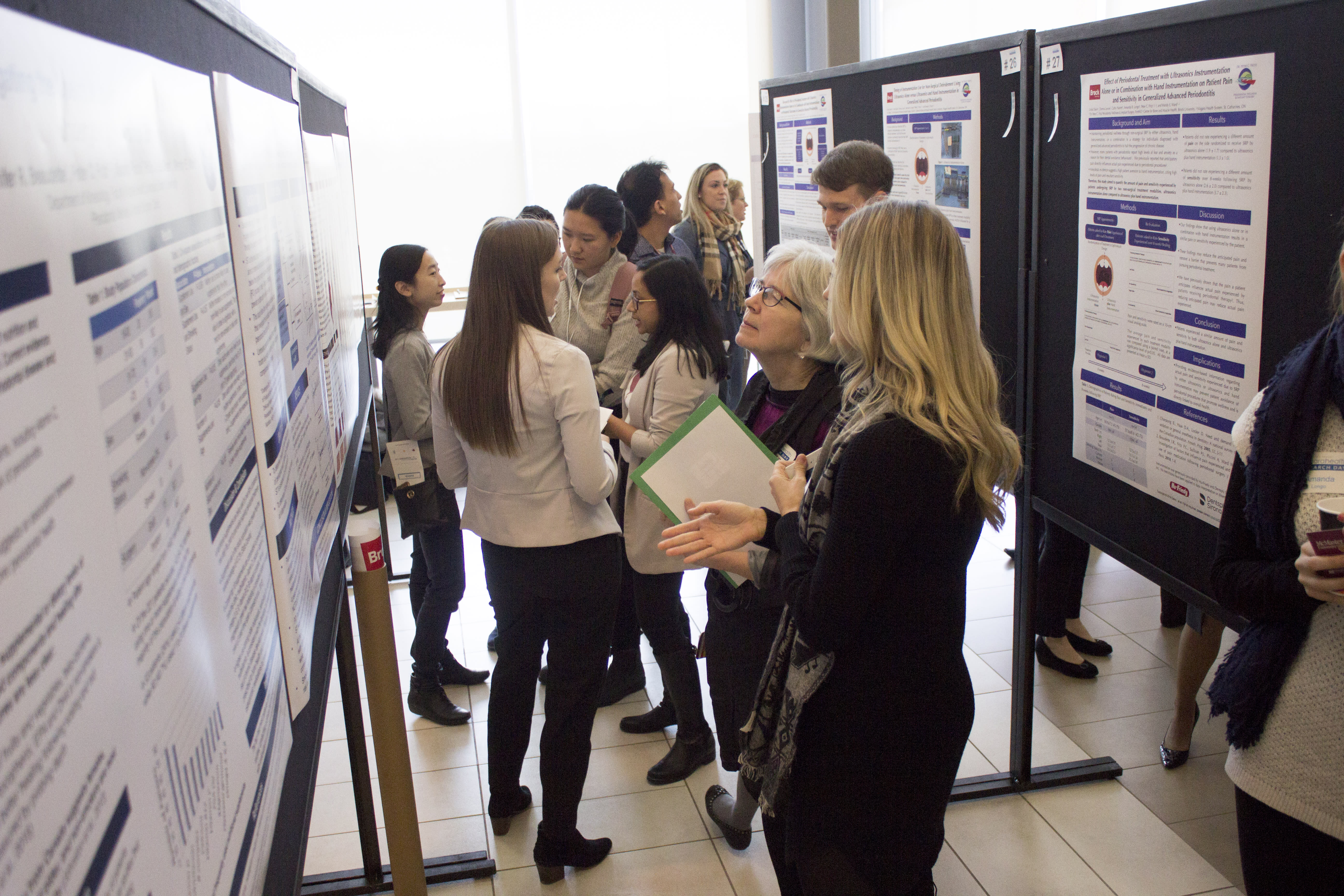 People gather around displays of posters describing research.