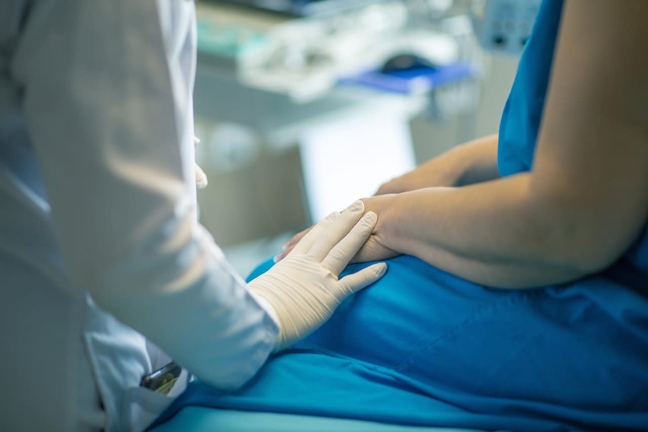 healthcare practitioner reassuring a patient by putting their hand on the patient's arm